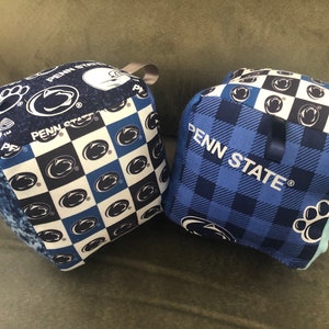 May include: Two blue and white Penn State University themed fabric cubes. One cube has a checkered pattern with the Penn State logo and the other has a blue and white plaid pattern with the words "Penn State" in white.