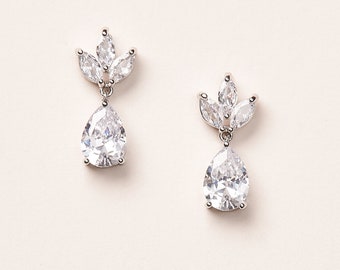 May include: A pair of silver teardrop earrings with a cluster of smaller clear stones at the top.