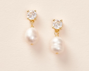May include: A pair of gold earrings with a small clear crystal and a white pearl dangling from each.