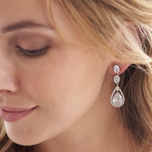 May include: Silver teardrop earrings with a large pear-shaped crystal surrounded by smaller crystals.