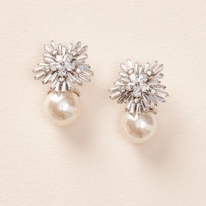 May include: A pair of silver earrings with a pearl drop and a crystal starburst design.
