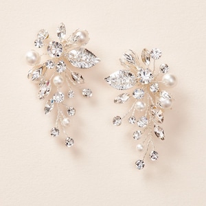 May include: A pair of silver bridal hair clips with pearl and crystal embellishments. The clips feature a delicate floral design with leaves and branches.
