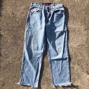 May include: Light blue denim jeans with a button fly and frayed hems.