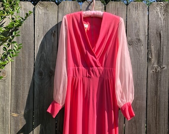 May include: A pink maxi dress with sheer pink sleeves. The dress has a V-neckline and a wrap-style bodice.
