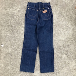 May include: A pair of dark blue denim jeans with a brown leather patch on the back pocket that says "Wrangler".