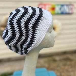 May include: A black and white striped crocheted beanie hat on a white mannequin head.