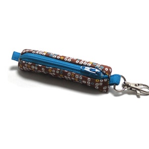 May include: A small brown zippered pouch with a white and yellow polka dot pattern. The pouch has a blue zipper and a silver metal key ring.