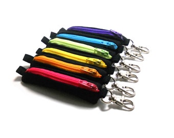 May include: A set of seven small zippered pouches in rainbow colors, each with a silver key ring. The pouches are lined up in order of the rainbow, with purple at the top and red at the bottom.
