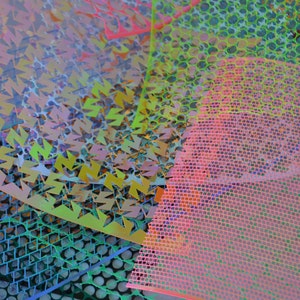 May include: A collection of colorful, patterned plastic sheets with geometric designs. The sheets are layered on top of each other, creating a vibrant and abstract image.