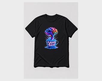 May include: A black t-shirt featuring a graphic of a blue teacup overflowing with a vibrant, multi-colored brain-shaped cloud. The text "The ADHD Teacup" is printed in white on the front of the cup, surrounded by blue liquid splashes.