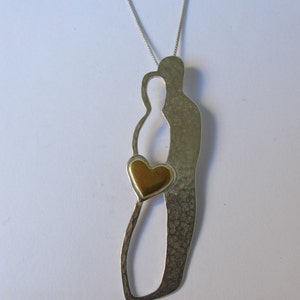 May include: A silver necklace with a pendant featuring two stylised figures holding a gold heart. The pendant has a textured finish.