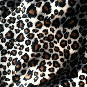 May include: Close-up of a white fabric with a brown and black leopard print pattern.