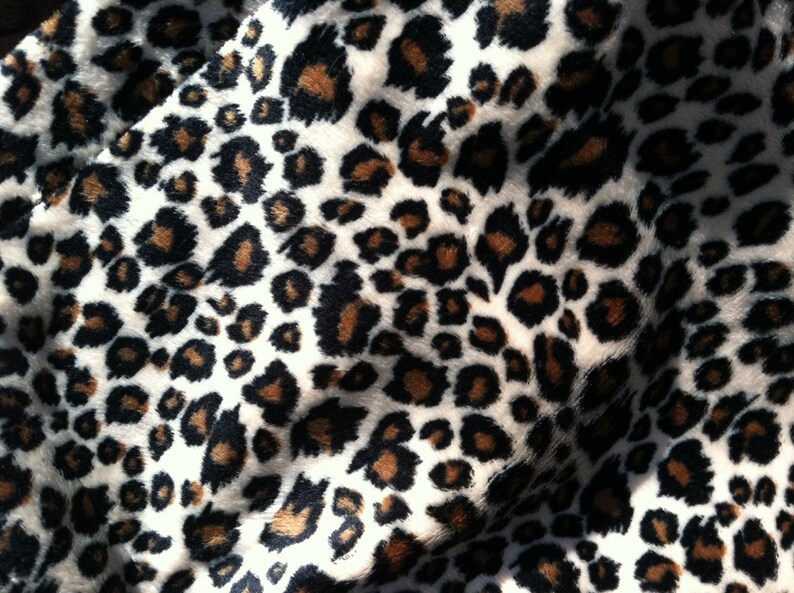 May include: Close-up of a white fabric with a brown and black leopard print pattern.