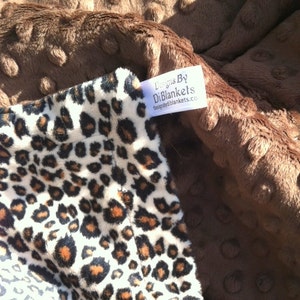 May include: A brown minky dot fabric blanket with a white and brown leopard print fabric on one side. The blanket has a white tag that says "Designs By DiBlankets thedesignsbydiblankets.com".
