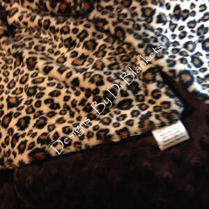 May include: A brown and tan leopard print fleece blanket with a brown minky backing. The blanket has the text "Designs By D.D. Blankets" printed on it.