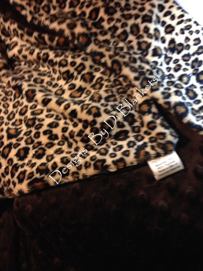 May include: A brown and tan leopard print fleece blanket with a brown minky backing. The blanket has the text "Designs By D.D. Blankets" printed on it.