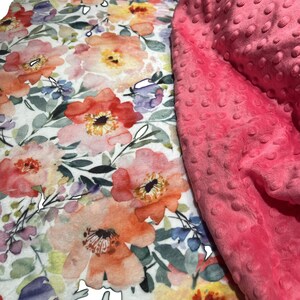 May include: A pink and white floral patterned fabric with a pink minky dot fabric overlay. The floral fabric features a watercolor style design with pink, orange, yellow, and purple flowers.