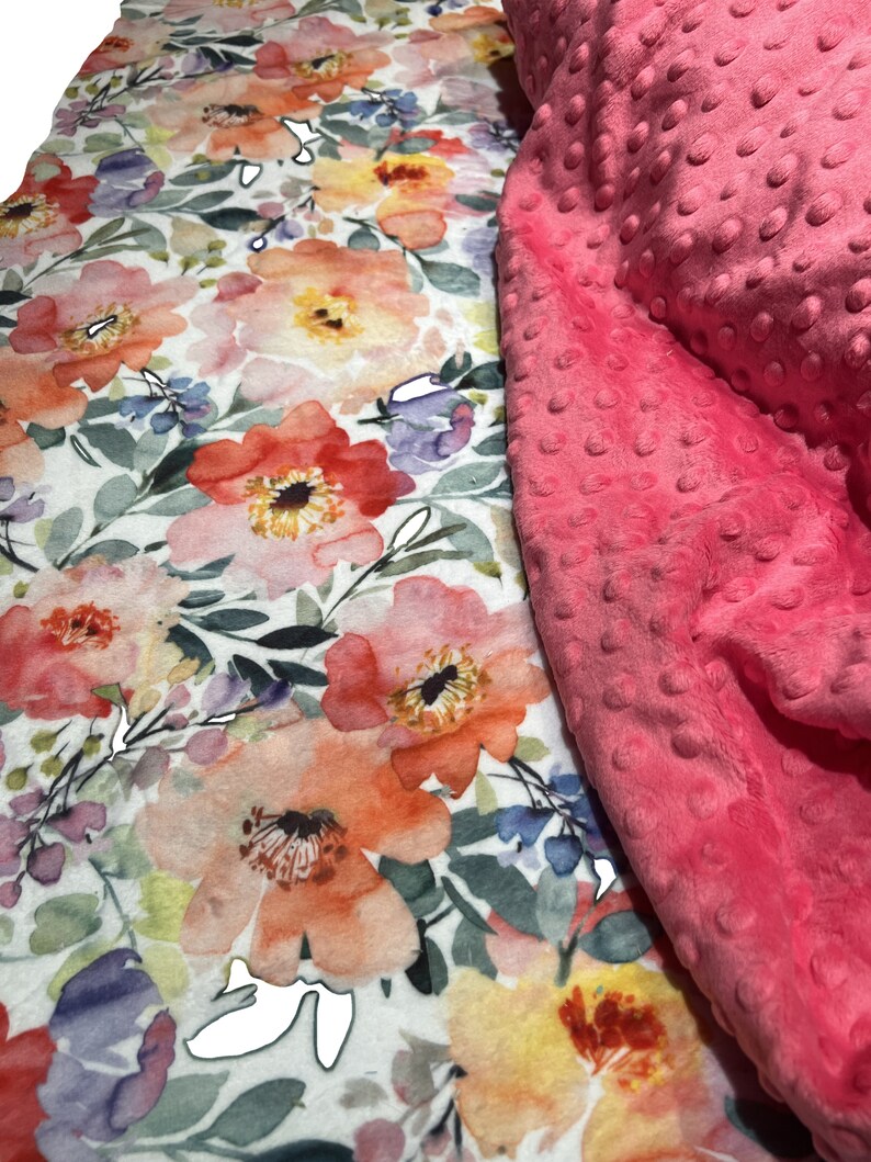 May include: A pink and white floral patterned fabric with a pink minky dot fabric overlay. The floral fabric features a watercolor style design with pink, orange, yellow, and purple flowers.