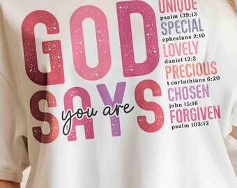 May include: White t-shirt with a pink and purple graphic that says "God Says You Are" with bible verses listed below. The verses are: Psalm 139:13, Ephesians 2:10, Daniel 12:3, 1 Corinthians 6:20, John 15:16, Psalm 103:12.