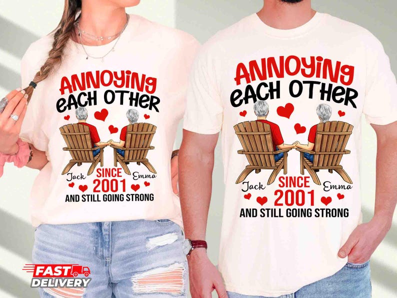 May include: Two off-white t-shirts featuring a graphic of two people sitting in wooden chairs, holding hands. The text reads: ANNOYING EACH OTHER SINCE 2001 AND STILL GOING STRONG, with the names Jack and Emma printed below the chairs and red hearts.