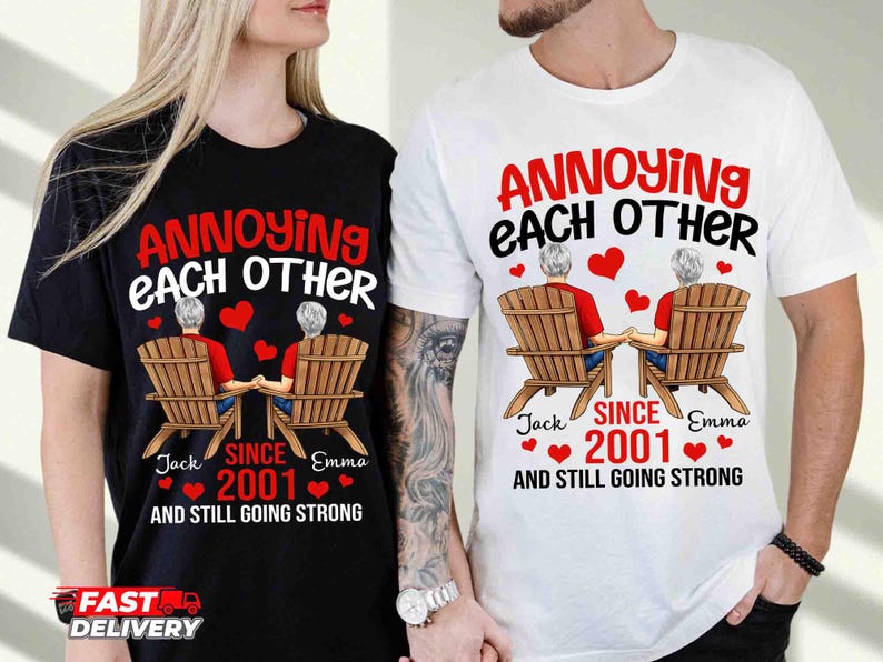 May include: A black t-shirt and a white t-shirt, each featuring a graphic of two people sitting in wooden chairs, holding hands, with red hearts and the text: ANNOYING EACH OTHER SINCE 2001 AND STILL GOING STRONG, with the names Jack and Emma.