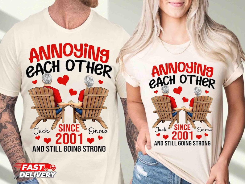 May include: Two cream-colored t-shirts featuring a graphic of two people sitting in wooden chairs holding hands. The text reads: ANNOYING EACH OTHER SINCE 2001 AND STILL GOING STRONG, with the names Jack and Emma printed below the chairs.