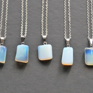 May include: Five silver chains with opal pendant necklaces. Each necklace features a rectangular shaped opal pendant with a light blue and white iridescent colour.