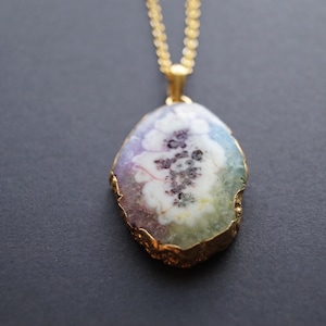 Peut inclure: Un collier en cha&icirc;ne dor&eacute;e avec un pendentif en forme d'agate ovale iris&eacute;e avec un bord dor&eacute;.