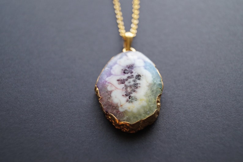 Peut inclure: Un collier en cha&icirc;ne dor&eacute;e avec un pendentif en forme d'agate ovale iris&eacute;e avec un bord dor&eacute;.