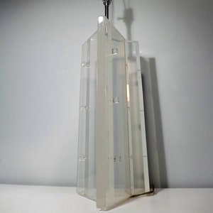 May include: A clear acrylic table lamp with a geometric design. The lamp has a metal base and a clear glass shade.