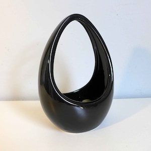 May include: A black ceramic vase with a unique teardrop shape and a large opening at the top. The vase is perfect for displaying flowers or other decorative items.
