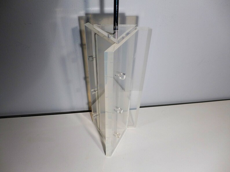 May include: A clear acrylic display stand with multiple tiers. The stand is made of clear acrylic and has a modern design.