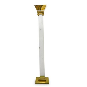 May include: A tall, clear glass floor lamp with a gold metal base and top. The base is square and the top is a triangular shape.