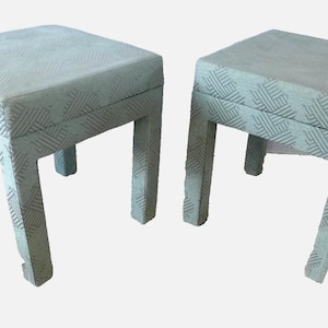 May include: Two square upholstered stools. The stools have a light green fabric with a geometric pattern. Each stool has four square legs. The stools are side by side.