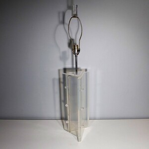 May include: A clear acrylic lamp base with a geometric design. The lamp base has a metal lampshade holder and a clear glass lampshade.