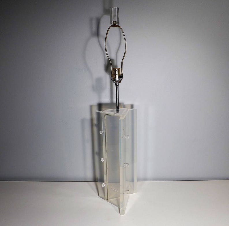 May include: A clear acrylic lamp base with a geometric design. The lamp base has a metal lampshade holder and a clear glass lampshade.