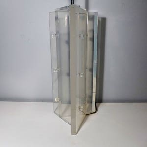 May include: A clear acrylic lamp base with a geometric design. The base is made of multiple panels that are joined together to create a unique shape.