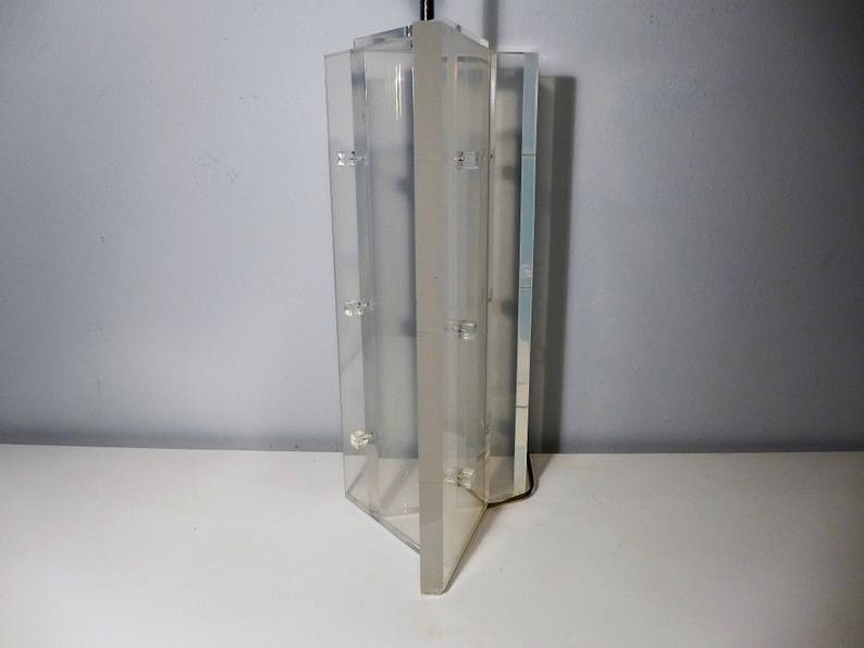May include: A clear acrylic lamp base with a geometric design. The base is made of multiple panels that are joined together to create a unique shape.