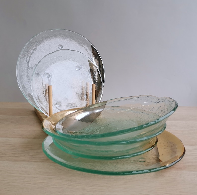 May include: Set of four clear glass plates with a textured surface. The plates are stacked on top of each other, with the largest plate on the bottom and the smallest plate on top.