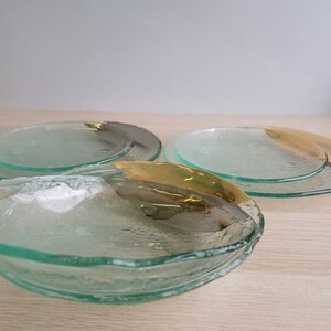 May include: Three glass plates with a textured surface and a gold rim. The plates are stacked on top of each other.