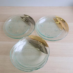 May include: Three clear glass plates with gold accents. The plates are stacked on top of each other. The plates have a textured surface.