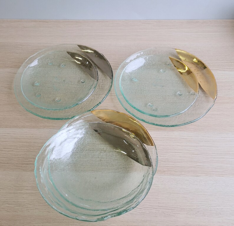 May include: Three clear glass plates with gold accents. The plates are stacked on top of each other. The plates have a textured surface.