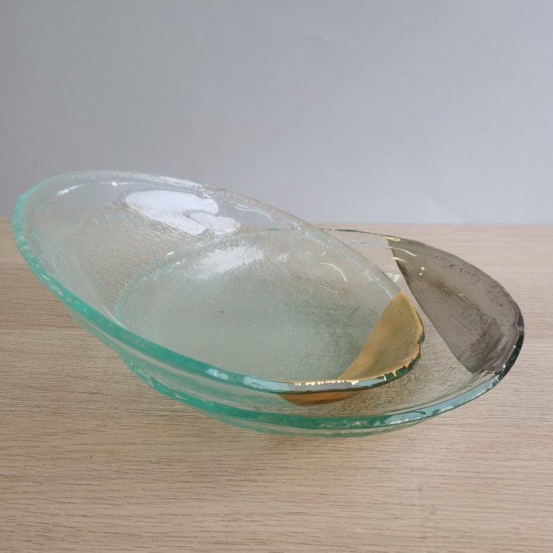May include: Two clear glass bowls with a textured surface. The top bowl has a gold accent and the bottom bowl has a gray accent.