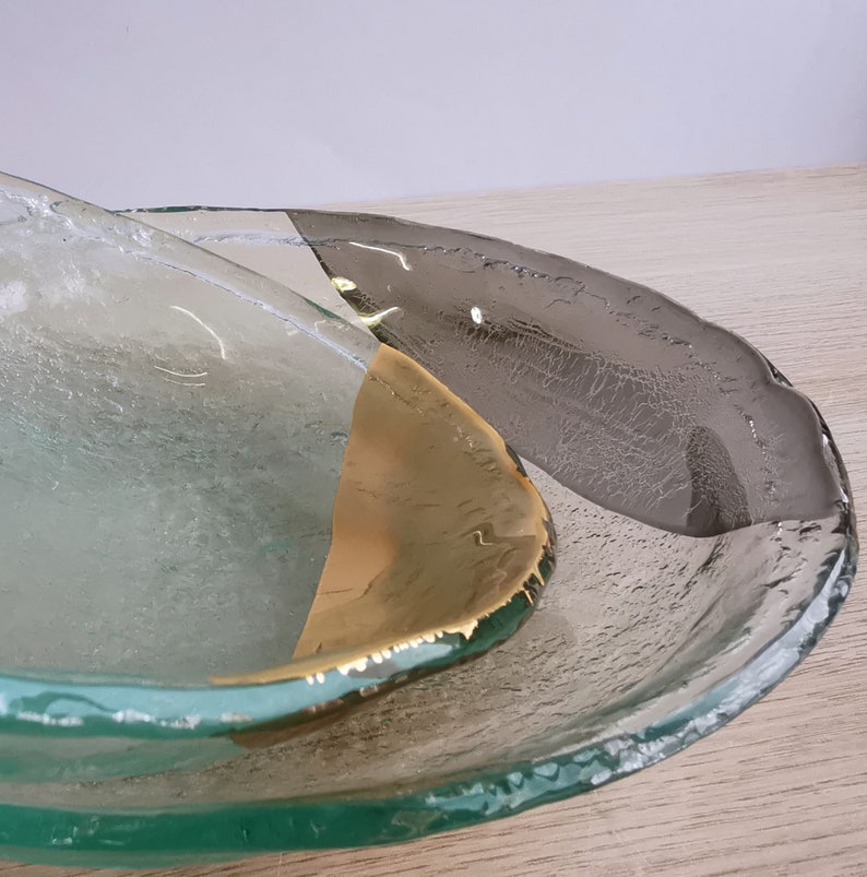 May include: Two clear glass bowls with a textured surface. The top bowl has a gold accent on the rim. The bowls are nested together.