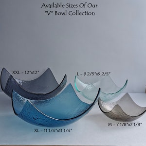 May include: A collection of textured glass bowls in various sizes and shades of blue, gray, and clear. The bowls have a unique V-shape design. Sizes include XXL (12"x12"), XL (11 1/4"x11 1/4"), L (9 2/5"x9 2/5"), and M (7 1/8"x7 1/8"). Text on the image reads "Available Sizes Of Our 'V' Bowl Collection."