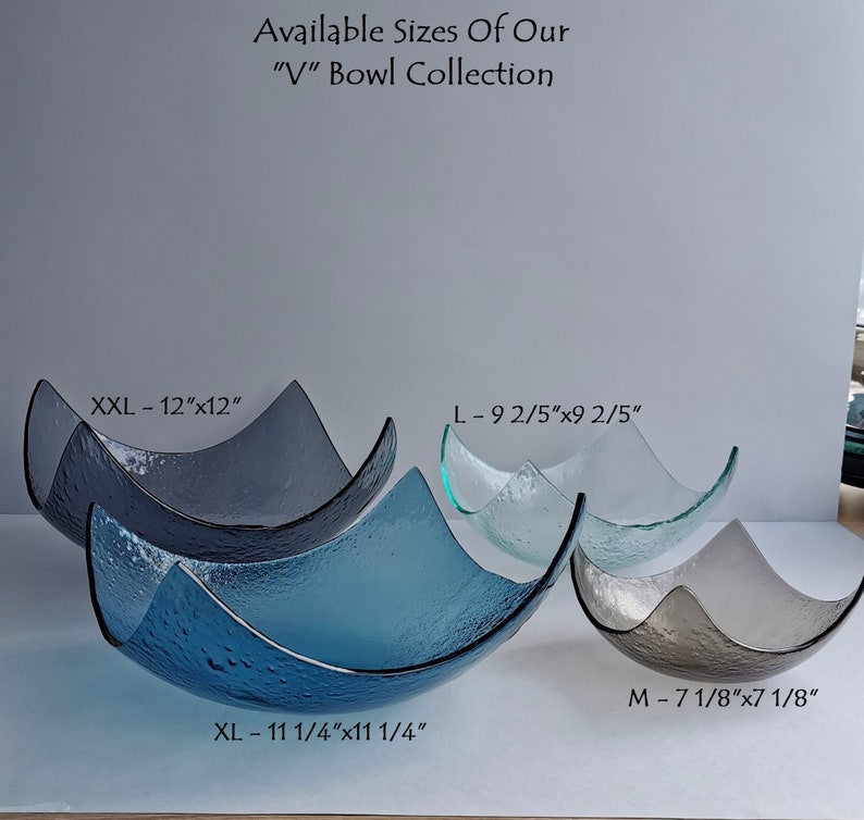 May include: A collection of textured glass bowls in various sizes and shades of blue, gray, and clear. The bowls have a unique V-shape design. Sizes include XXL (12"x12"), XL (11 1/4"x11 1/4"), L (9 2/5"x9 2/5"), and M (7 1/8"x7 1/8"). Text on the image reads "Available Sizes Of Our 'V' Bowl Collection."