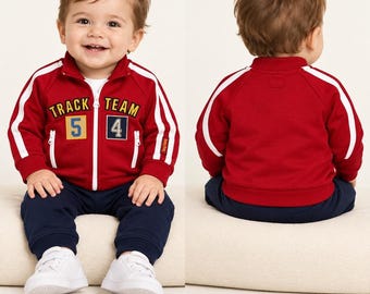 Puede incluir: Una chaqueta deportiva roja con cremallera, rayas laterales blancas y el texto "TRACK TEAM 54" en el pecho, combinada con pantalones de chándal azul marino y zapatillas blancas. Etiquetada "BABYGAP 12-18 MONTHS", vista frontal y trasera.