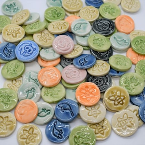 May include: A collection of colorful ceramic tiles with various animal and floral designs. The tiles are round and have a smooth, glossy finish.