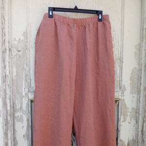 May include: A pair of wide-legged, salmon-colored linen pants with a relaxed fit and an elastic waistband.