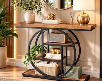 May include: A rectangular console table with a brown wood-grain finish and a black metal frame featuring a circular design. The table includes multiple shelves holding a Marshall speaker, books, a woven basket, a green box, and decorative items.